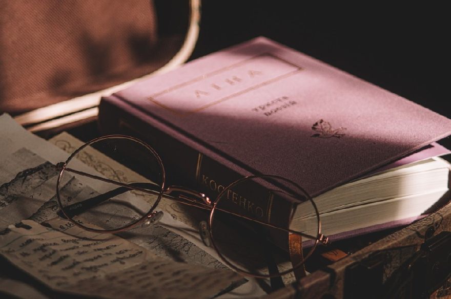 A pair of glasses with a newspaper and a book