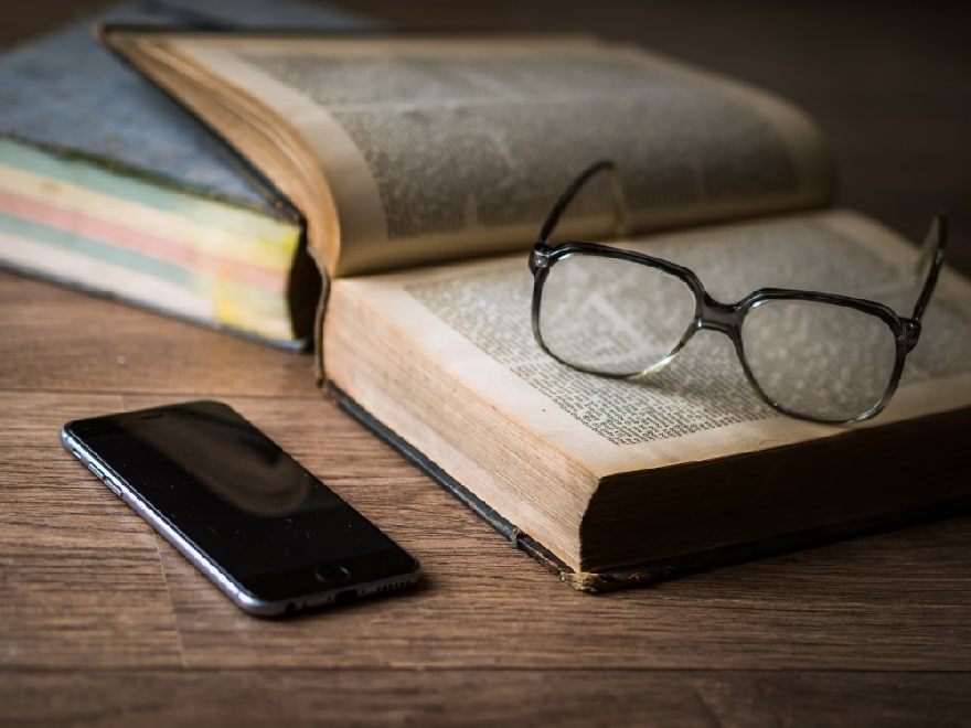 Des lunettes ainsi qu'un livre ouvert et un smartphone