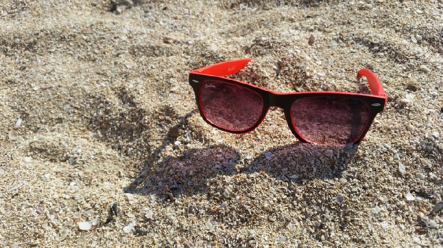 Rote Sonnebrille im Sand