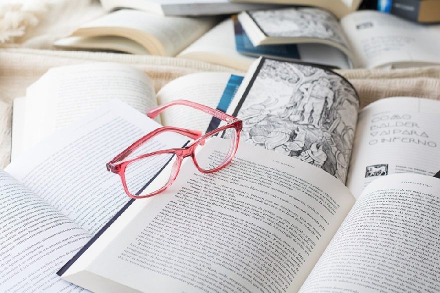 Pink glasses on many open books