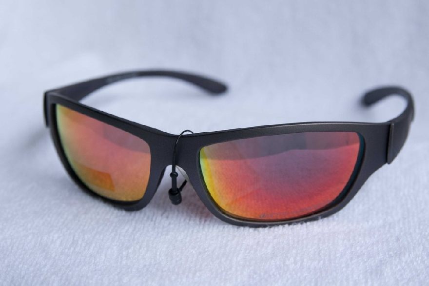 Black sunglasses with half-red lenses on a white background