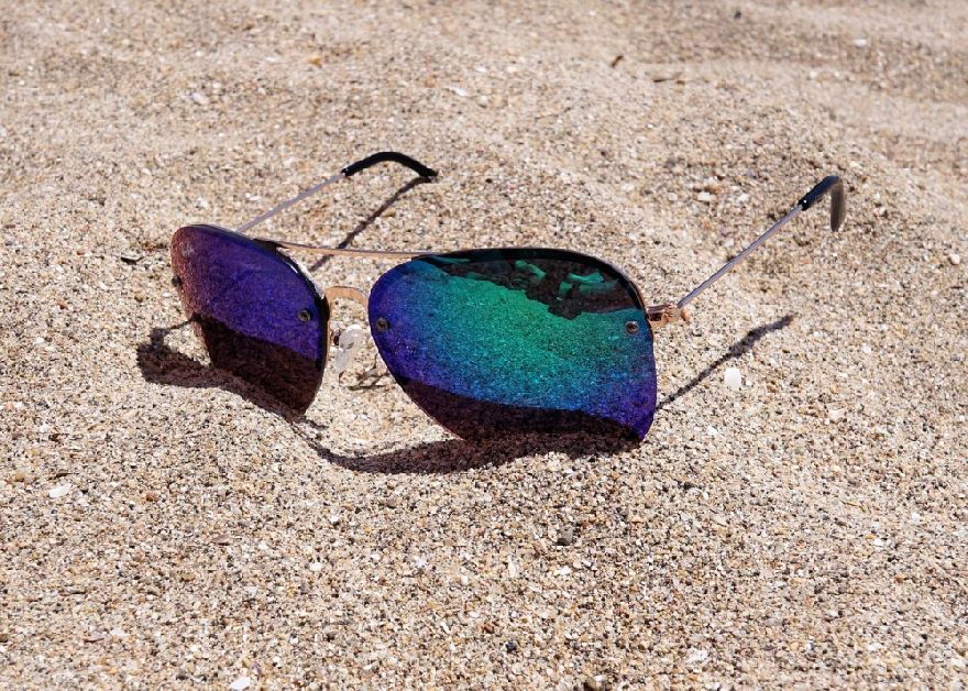 Blaue Sonnenbrille im Sand