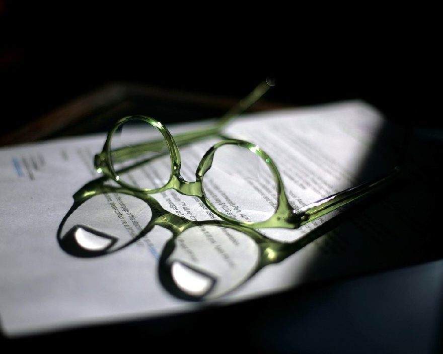 Grüne Brille auf einem Buch im Halbschatten